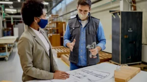 Truck dispatch professionals reviewing load plans and logistics strategies in a warehouse setting, discussing freight rate negotiation tips for profitable shipments.